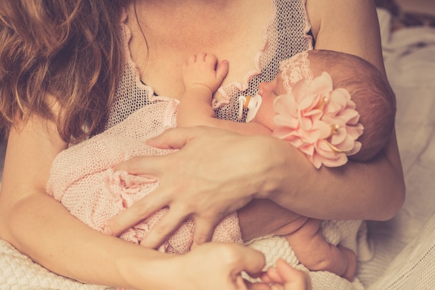 Mom holds her adorable sleeping newborn baby girl in her arms and looks at her. 