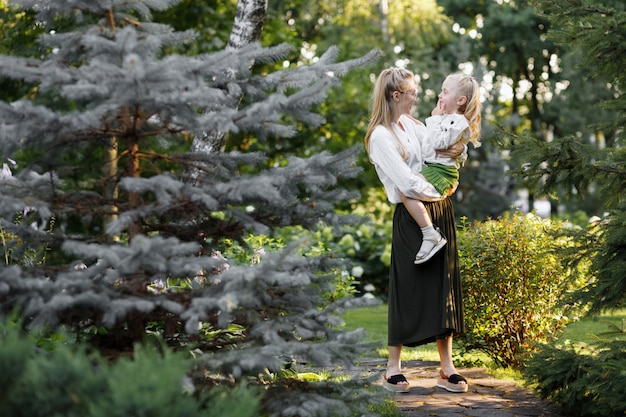 Mom holds her daughter in her arms in the summer on a walk. Happiness