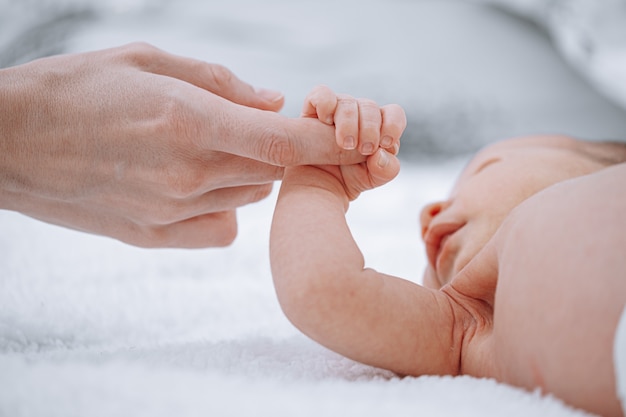 Mom holds newborn baby by the hand