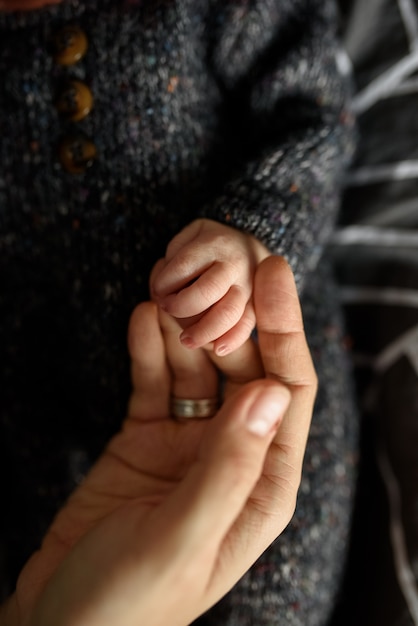 Mom holds the tiny hand of her newborn son.