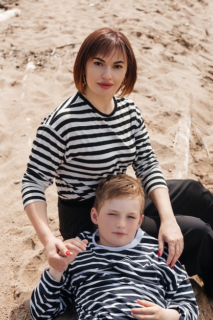 Mom hugs her son on the riverbank. A beautiful, modern mother with a happy son in striped vests.