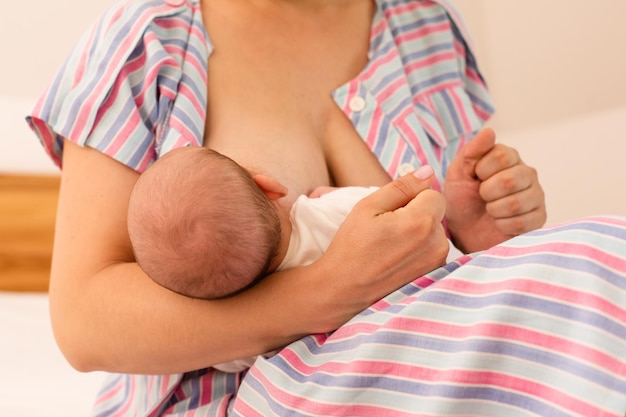 The mom is breastfeeding her newborn baby on the bed