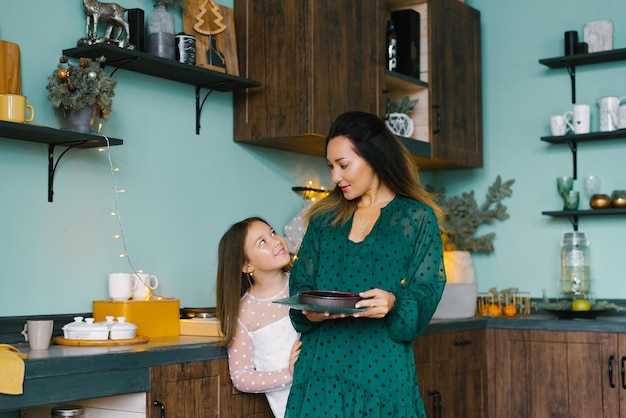 Mom is holding a pie with berries in her hands daughter is enjoying the Christmas holiday at home