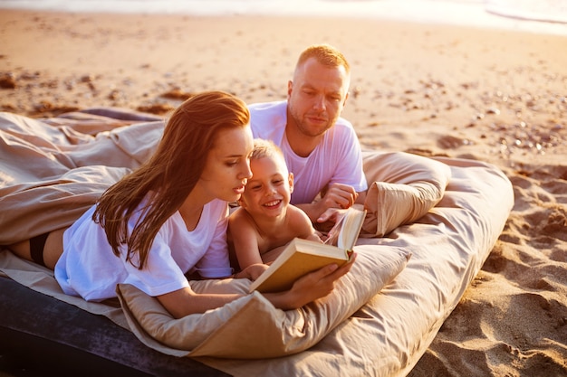 Mom is reading a book to her son while lying on the bed