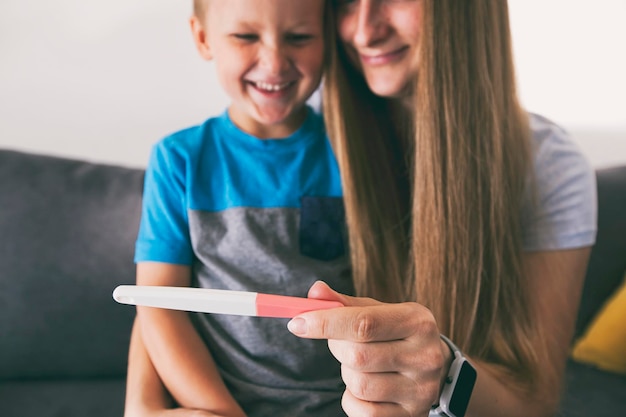 The mom is showing her son the pregnant test