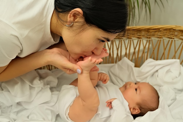 Mom kisses the legs of a newborn baby the concept of a kiss motherly love