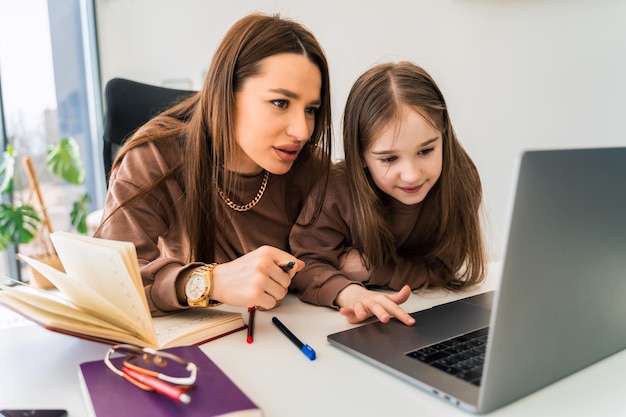 Mom and little daughter doing homework on laptop