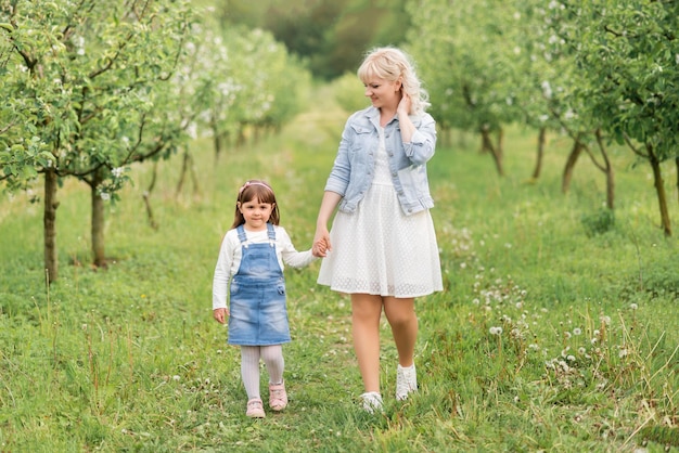 Mom and little daughter walking in the spring garden