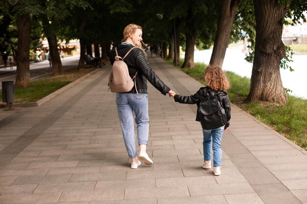 The mom and little girl walk together along the waterfront