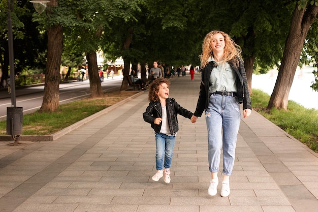 The mom and little girl walk together along the waterfront