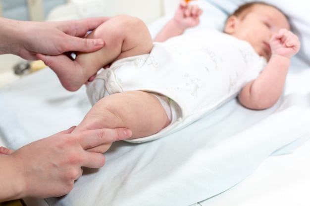 Mom makes exercise smiling child. baby newborn is enjoying massage from mother