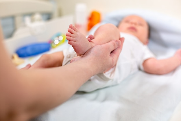 Mom makes exercise smiling child. baby newborn is enjoying massage from mother