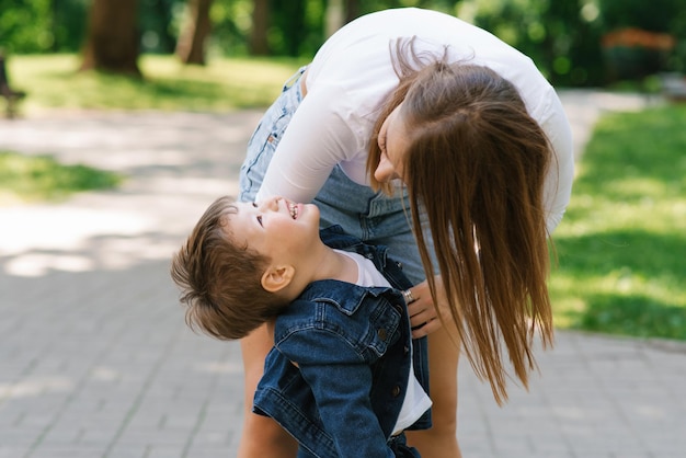 Mom and son are actively playing having fun outdoors in the summer in the park Happy motherhood childhood youth Taking care of children