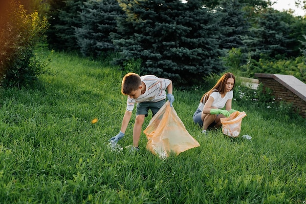 Mom and son are cleaning garbage in the park at sunset Environmental care waste recycling