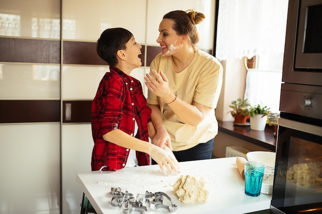 Mom and son are cooking together in kitchen, preparing dough for cookies