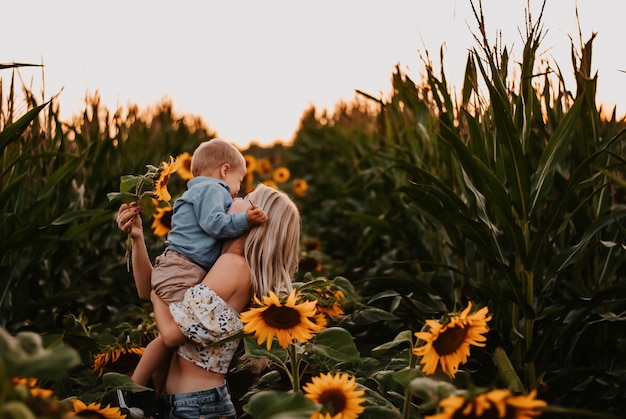 mom and son are happy mom and baby are smiling field of sunflowers the setting sun