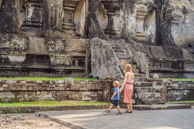 Mom and son on background of Gunung Kawi. Ancient carved in the stone temple with royal tombs. Bali, Indonesia. Traveling with children concept..