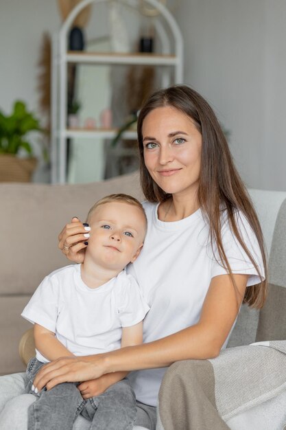 Mom and son at home in the living room hugging and playing parenthood of a young single mom and her