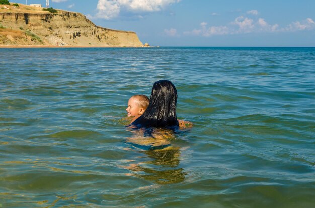 Mom and son swim in the sea on a summer day.