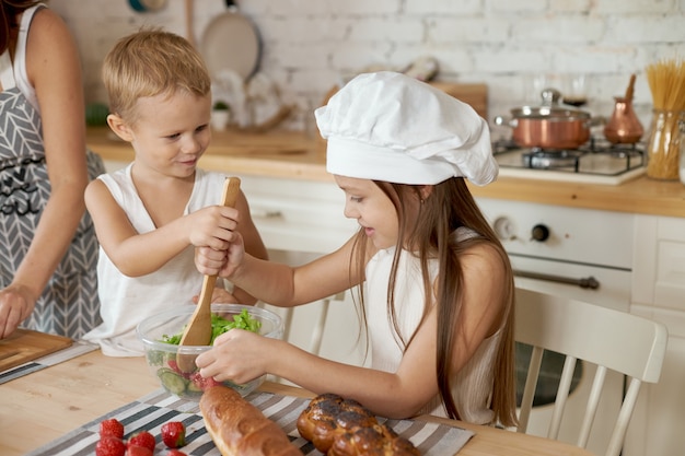 Mom teaches her daughter and son to prepare a Salad of fresh vegetables