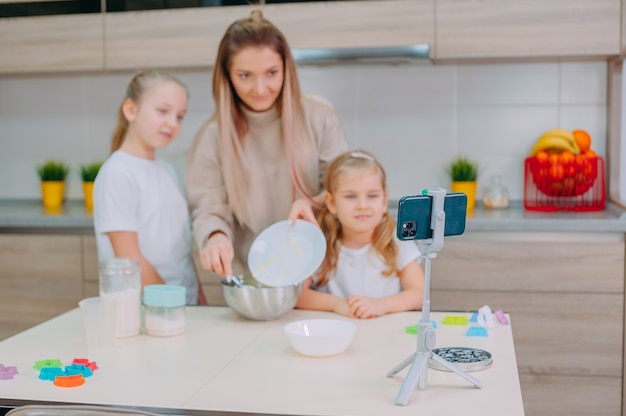 Mom teaches her daughters to cook dough in the kitchen