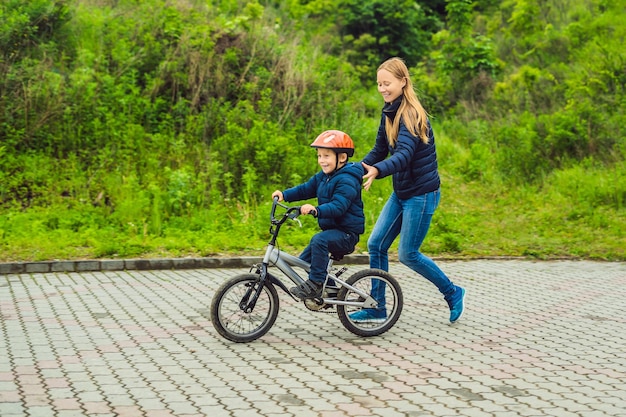 Mom teaches son to ride a bike in the park