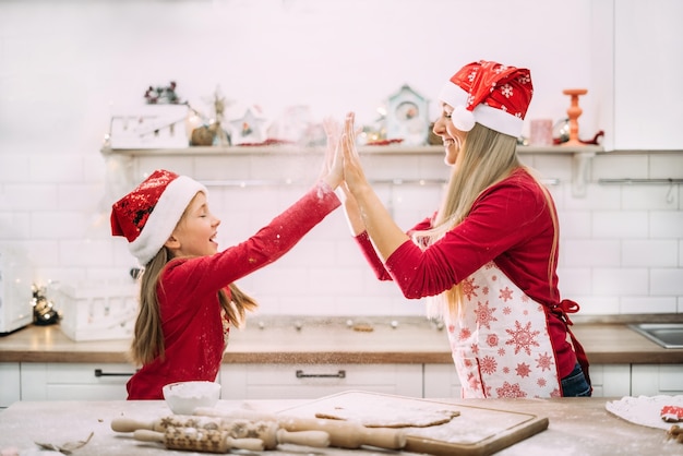 Mom and teenage daughter are playing in the kitchen with flour