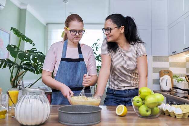 Mom and teenage daughter preparing apple pie together