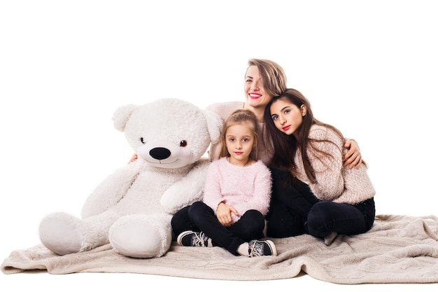 Mom and two daughters sit on the blanket and embrace