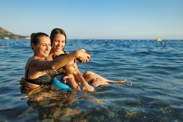 Mom and two daughters take a selfie while swimming in the sea