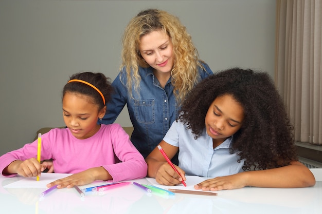 Mom watches as her daughter drawing with crayons