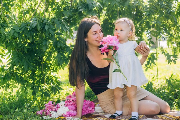 Mom with a baby in her arms on a sunny day walks through the park.