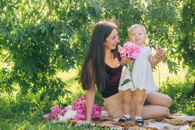 Mom with a baby in her arms on a sunny day walks through the park.