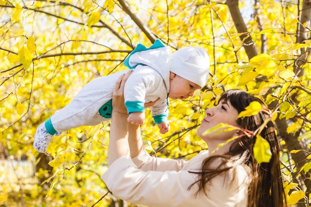 Mom with a baby, a small boy walks in the fall in the Park or forest. Yellow leaves, the beauty of nature. Communication between a child and a parent.