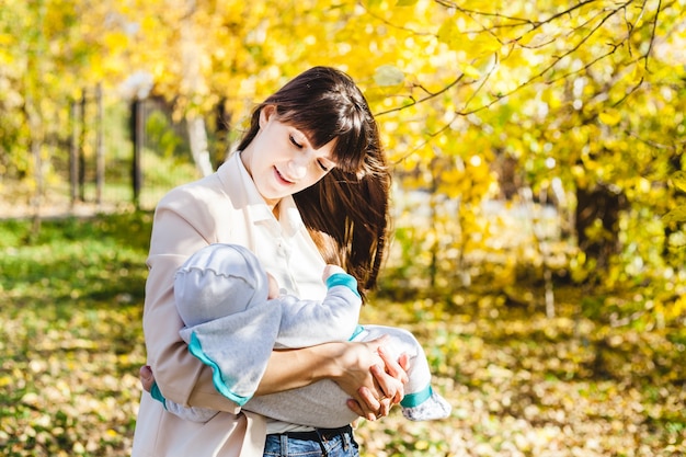 Mom with a baby, a small boy walks in the fall in the Park or forest. Yellow leaves, the beauty of nature. Communication between a child and a parent.