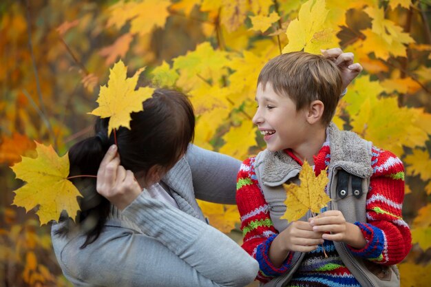 Mom with a child on an autumn walk in yellow leaves