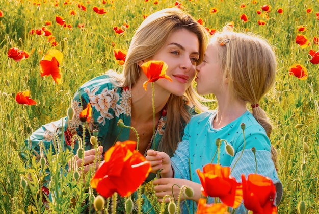 Mom with a child girl in a field of red poppies enjoys nature mother and little daughter in the popp