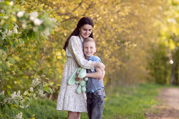 Mom with dark hair hugs her son and looks at him