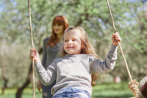 Mom with her little daughter on the swing. the concept of parenting