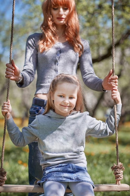 Mom with her little daughter on the swing.