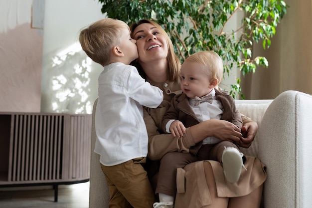 Mom with two adorable sons one of whom kisses her on the cheek mothers day concept