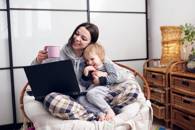 Mom working with laptop computer at home and playing with her baby.