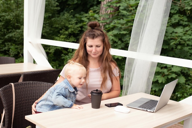 Mom works at a laptop in a cafe, the child interferes with work and communication,a place to copy