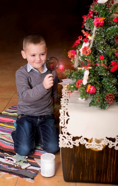 Moments of childhood christmas holidays concept a boy next to the christmas tree at home the child