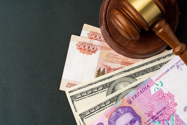 Money banknotes with judge gavel. Corruption concept with currency of Russian Rubles, Ukrainian Hryvnia and American Dollars