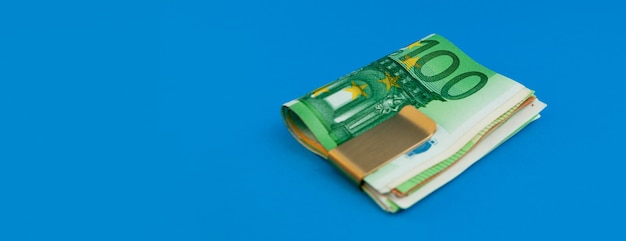 Money clip with euro bills on blue background