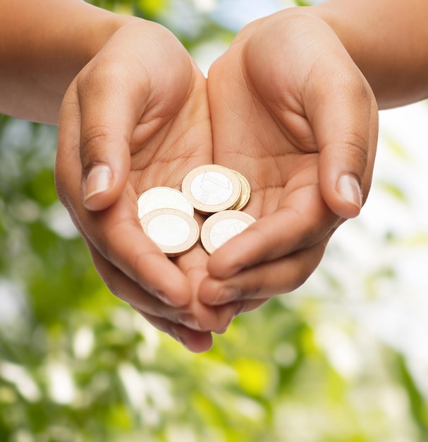 money and finances concept - close up of womans cupped hands showing euro coins