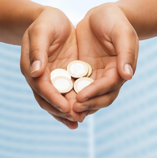 money and finances concept - close up of womans cupped hands showing euro coins