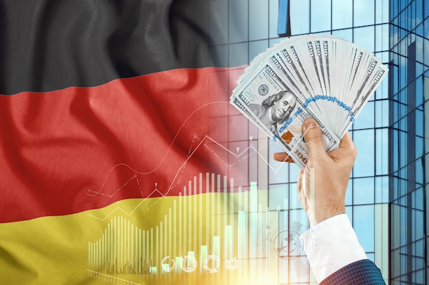 Money in a man's hand against the background of the flag of Germany. Nemtsov's income. The financial condition of residents of Germany, taxes, loans, mortgages. State debt of the country.