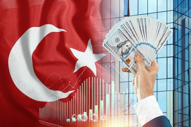 Money in a man's hand against the background of the flag of Turkey